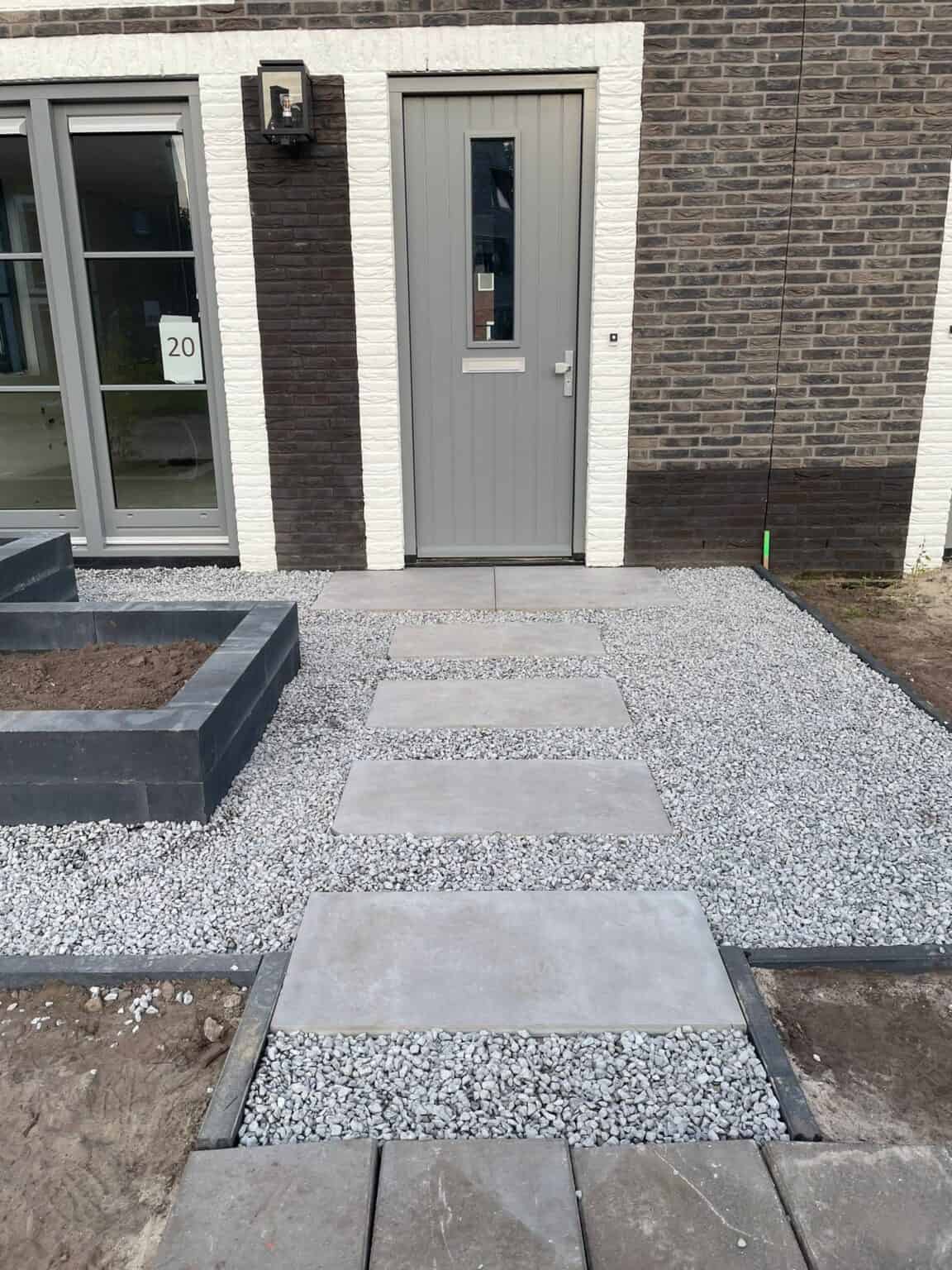 Nieuwe tuin- en opritbestrating met grind en betonplaten voor een moderne uitstraling.