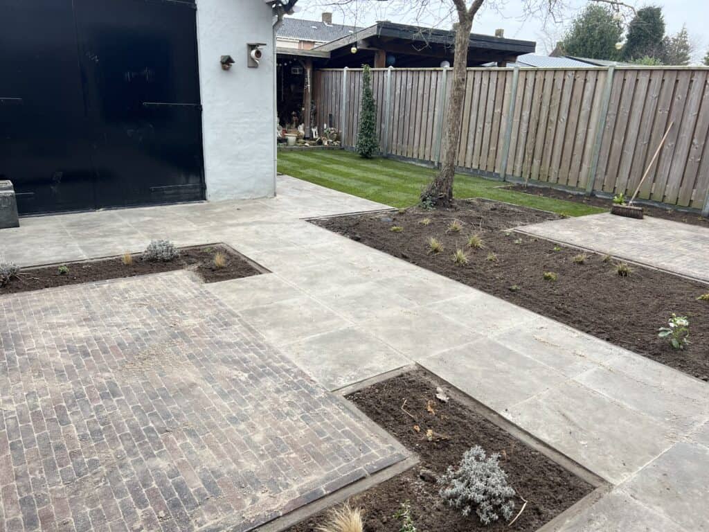 Kleurrijke tuin met betegeld terras, plantenbakken en groene tuin, tuinontwerp door vdhoogenhoveniers.