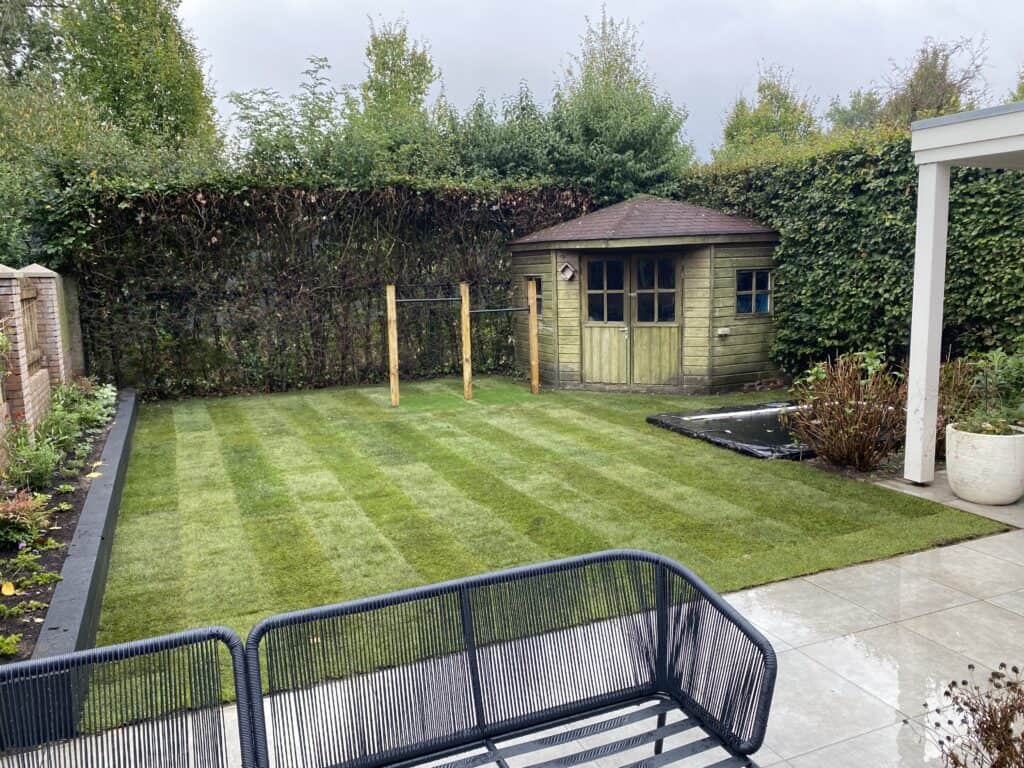 Strak onderhouden gazon en tuin met speelhuisje in achtertuin.