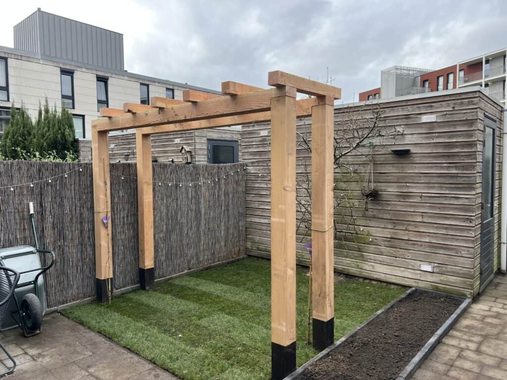 Houten tuinpergola in aanleg voor schaduw en decoratie.