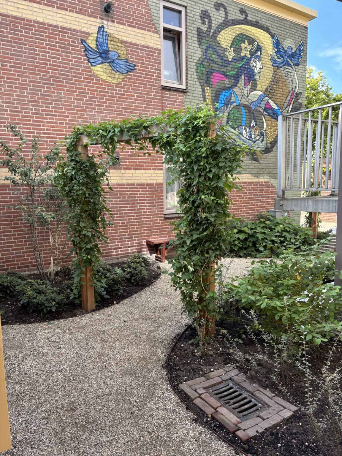 Kunst in de tuin met muurschildering en groene beplanting, duurzame tuinontwerp, groen ontwerp, tuinarchitectuur.