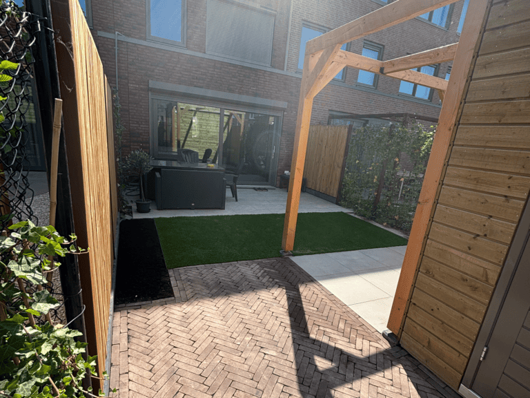 Nieuwe tuin met verhoogde zitplek en sierbestrating voor gezellige buitenruimte.